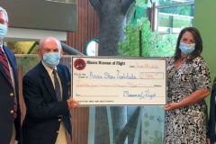 board members holding large check for donation from museum