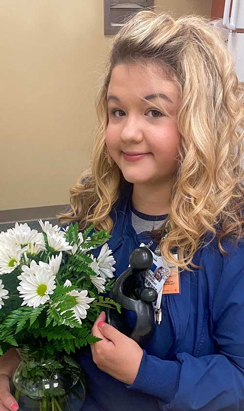 Hannnah Nicholson is the  nurse who won the daisy award pictured with her flowers and her award statue