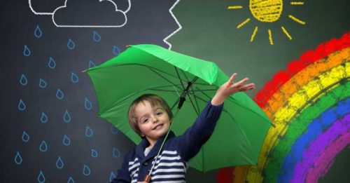 young boy with umbrella in front of chalkboard wall with rainbow